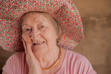 Portrait of elderly woman in pink T-shirt with decorations and glasses. Pensioner supports health and looks great with beautician bag