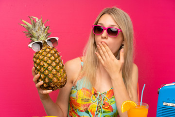 Young blonde woman in swimsuit holding a pineapple with sunglasses