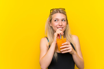 Young woman in swimsuit over yellow background with a cocktail