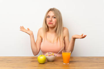 Young blonde woman having breakfast having doubts with confuse face expression