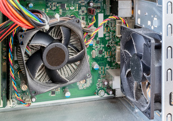 The interior casing of a PC computer showing very dusty cooling fans, sinks and circuit board