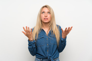 Young blonde woman over isolated white wall frustrated by a bad situation