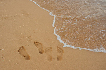 Footprints of human feet on the sand near the water on the beach