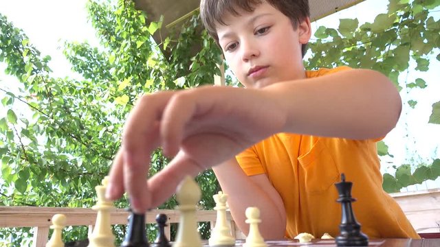 The boy plays chess summer outdoors