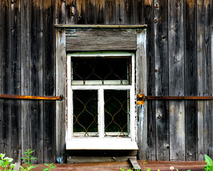 Window with the wooden carved architrave in the old wooden house in the old Russian town.