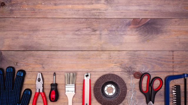 Different DIY tools moving on wooden background with copyspace. Top view. Stop motion animation. 4k.