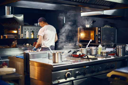 cook stands with his back, Cooking in a modern kitchen, in a restaurant. low key. Copy space for text