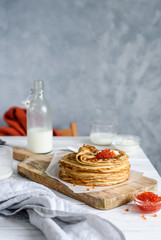 Russian pancakes with red caviar on a white table 