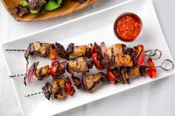 Pork shish kabob skewers viewed from above. These delicious pork meat souvlaki were roasted on the bbq until well-grilled. Cooking food on skewers has been common in many cuisines since ancient times.