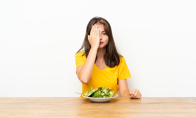 Caucasian girl with salad covering a eye by hand