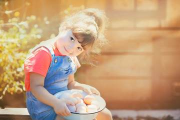 Adorable little girl holding basket full of white and brown raw eggs