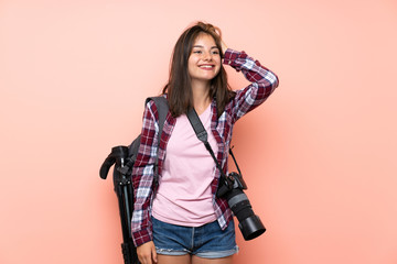 Young photographer girl over isolated pink background laughing