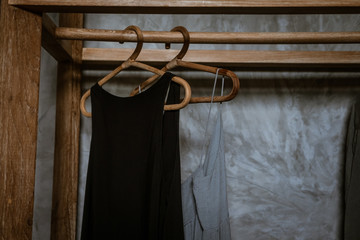 Boho chic Little black dress hanging on a  clothing rack, rappan wooden hangers. Boho chic style. Fashion blogging concept, neutral colors. Loft bedroom interior design wooden clothing rack