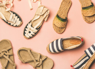 Variety of trendy woman's summer shoes. Flat-lay of espadrilles, sandals, flip flops made of natural materials over pastel pink background, top view. Summer season footwear apparel concept