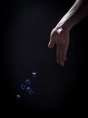 A Caucasian Man's Hand Tossing Blue Role Playing Dice - with a Black Background
