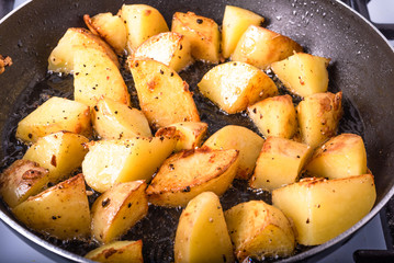 Cooking a rustic breakfast - large pieces of potatoes are fried in a pan