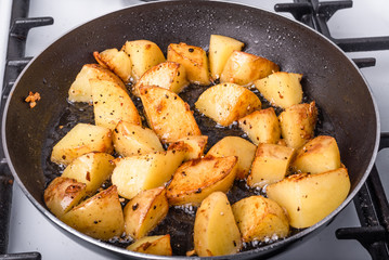 Cooking a rustic breakfast - large pieces of potatoes are fried in a pan