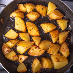 Cooking a rustic breakfast - large pieces of potatoes are fried in a pan