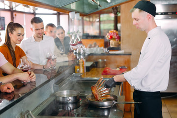 The chef prepares food in front of the visitors in the restaurant