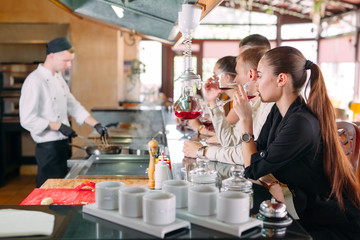 The chef prepares food in front of the visitors in the restaurant