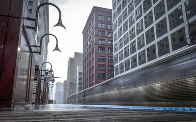 Ground Level View of a Speeding Train Car Passing by a Platform in the City of Chicago, Illinois on a Rainy Day - with Tall Buildings in the Background