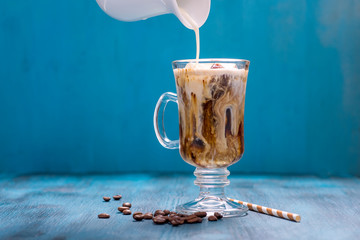 Iced coffee in a glass on blue background copy space