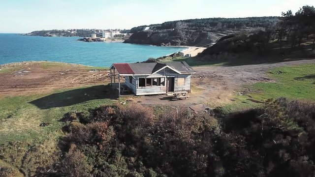 Aerial sea landscape with an old wooden shack in the foreground and modern hotes in the distance. Hidden Beach of Riva Elmas Burnu Nature Park in Istanbul