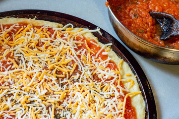 Raw uncooked homemade pizza and sauce on grey worktop, top down view