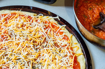 Raw uncooked homemade pizza and sauce on grey worktop, top down view