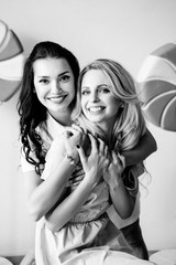 Fototapeta premium Brunette and blonde with bright dresses on a yellow background. Pink and yellow dress. Big lollipop.