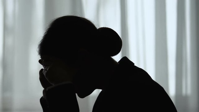 Silhouette of tired woman holding head, overworked and depressed, closeup