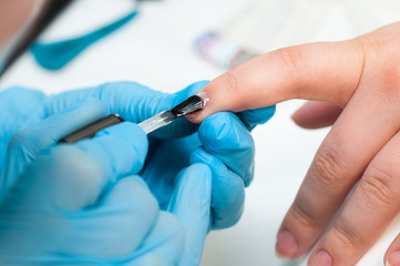 Nail Care And Manicure. Closeup Of Beautiful Female Hands Applying Transparent Nail Polish On Healthy Natural Woman's Nails In Beauty Salon. Manicurist Hand Painting Client's Nails.