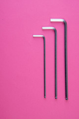 Three allen wrenches sorted by size on pink