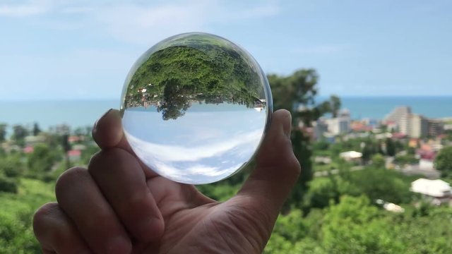 hand holding magic crystall ball over beautiful nature landscape, travel concept