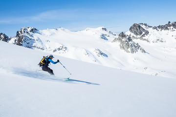 Skier on sunny slope of the Talkeetna Mountains in spring time. Fresh Alaska backcountry snow above...
