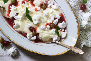 Eton mess, traditional English dessert with gooseberry, whipped cream and meringue on a light...