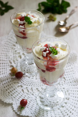 Eton mess, traditional English dessert with gooseberry, whipped cream and meringue on a light background. Rustic style.