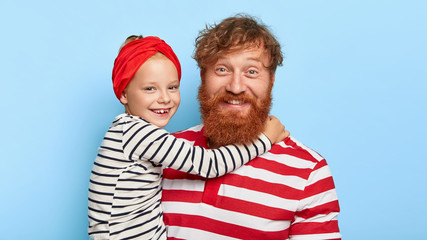 Portrait of cheerful red haired father and daughter make photo together, little child embraces with...