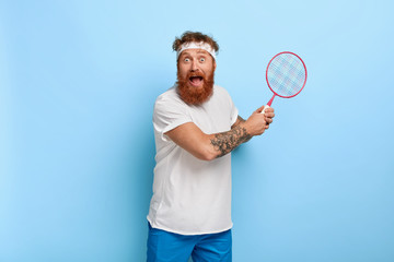 Scared foxy professional tennis player holds racket, afraids to miss ball, being in action, screams from emotions received during game, works hard, enjoys game, poses indoor. Recreation concept