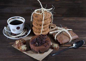 Sweet dessert with coffee, chocolate cheesecake, stack of oatmeal cookies and gingerbread on dark wooden background, mood
