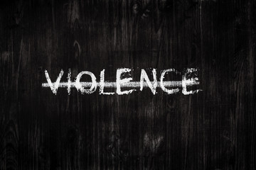 Violence word crossed out on black wood background. Sign, concept of dealing with abusive  issues - the word "violence" on a blackboard