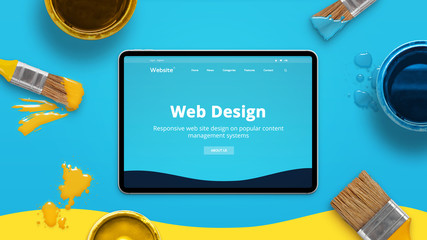 Web design concept with modern flat design theme on a thin tablet surrounded by color brushes and...