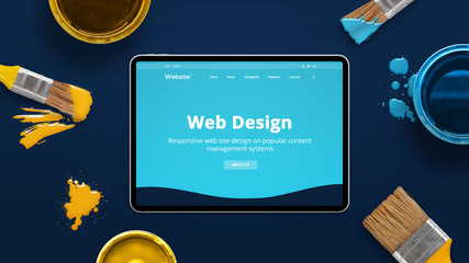 Modern tablet on a blue desk with creative flat design theme od web design studio. Concept of...