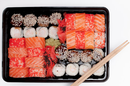 Big sushi set ib black plastic box on white background, top view close up, copy space