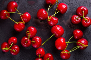Obraz na płótnie Canvas Cherries on a slate board. Sweet cherries on a dark background. Red berries in drops of water on black boards. Healthy food. Top view. Copy space