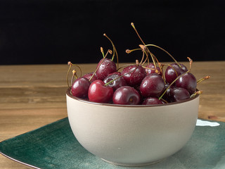 Delicious juicy cherries,lying on a beautiful plate.On wood background