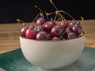 Delicious juicy cherries,lying on a beautiful plate.On wood background