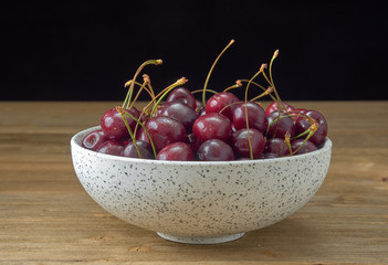 Delicious juicy cherries,lying on a beautiful plate.On wood background