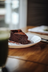 Slice of vegan chocolate One slice of vegan chocolate brownie cake on wooden table. Sugar free, wheat free, dairy free, flourless dessert. Dark mood food photo. Healthy eating, lifestyle concept. cake