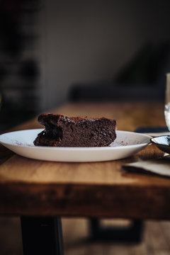 Slice of vegan chocolate One slice of vegan chocolate brownie cake on wooden table. Sugar free, wheat free, dairy free, flourless dessert. Dark mood food photo. Healthy eating, lifestyle concept. cake